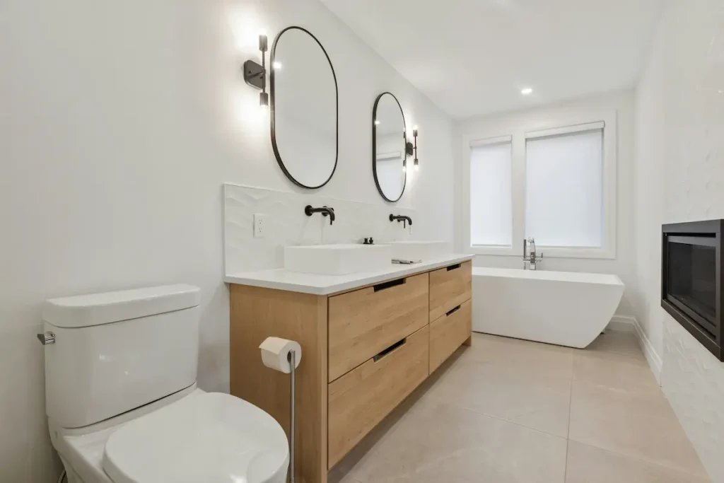 Luxury bathroom renovation with wood double vanity, freestanding tub, and fireplace by our Burlington team