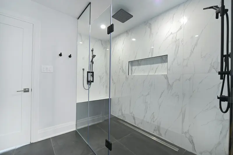 Modern walk-in shower with frameless glass and marble tile, converted from a bathtub in Burlington