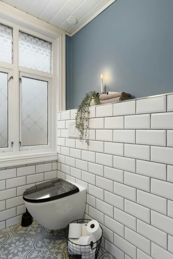 White subway wall tile and patterned floor tile in a renovated powder room