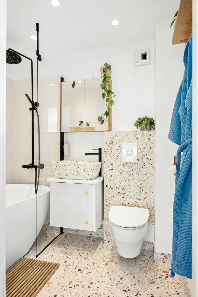 Terrazzo-style speckled floor and wall tile in an Alton Village, Burlington bathroom, with a wall-hung toilet and floating vanity