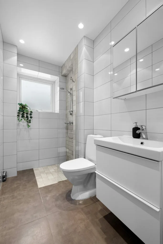White ceramic tile bathroom in Burlington with glass shower divider, mosaic shower tile niche, and large-format floor tile