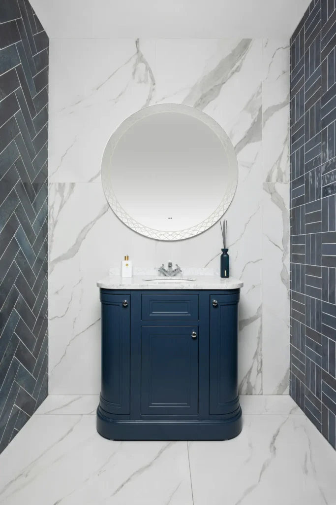 Custom bathroom tile pattern work in Burlington with herringbone side tile, large marble slab walls, and navy vanity
