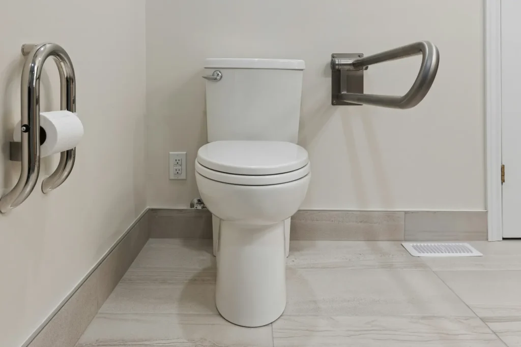 Accessible Burlington bathroom with stainless fold-down grab bars on both sides of the toilet and integrated toilet paper holder