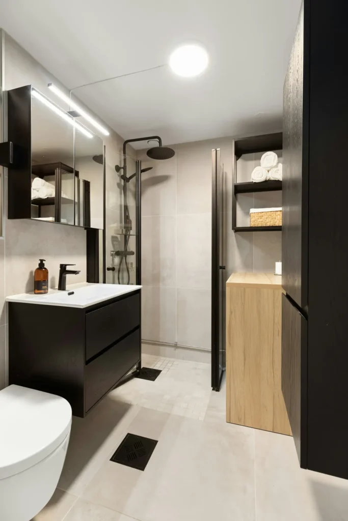 Modern full bathroom renovation with a dark wood vanity, open rain shower, and built-in storage cabinetry