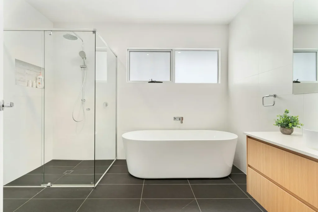 Full bathroom renovation in Alton Village, Burlington with a glass shower enclosure, freestanding tub, and wood-tone vanity
