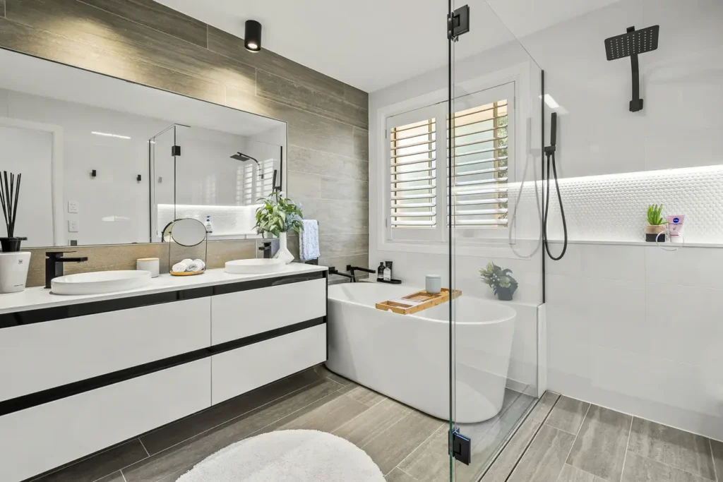 Modern full bathroom renovation with a black double vanity, freestanding tub, and glass shower enclosure