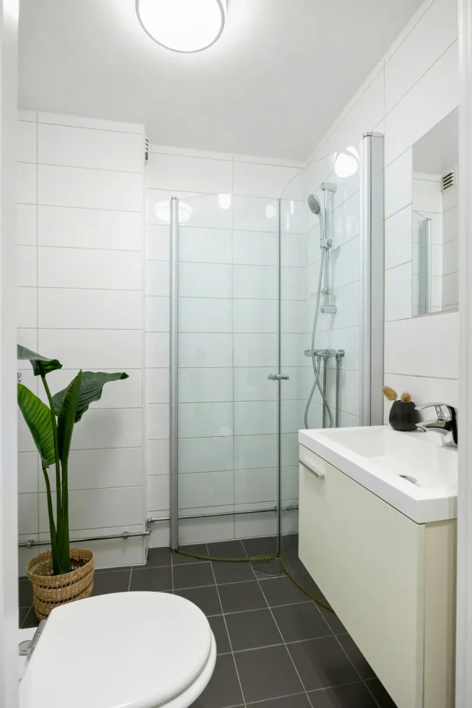 Full bathroom renovation in Headon Forest, Burlington with a glass-enclosed shower, floating white vanity, white tile walls, and dark tile flooring