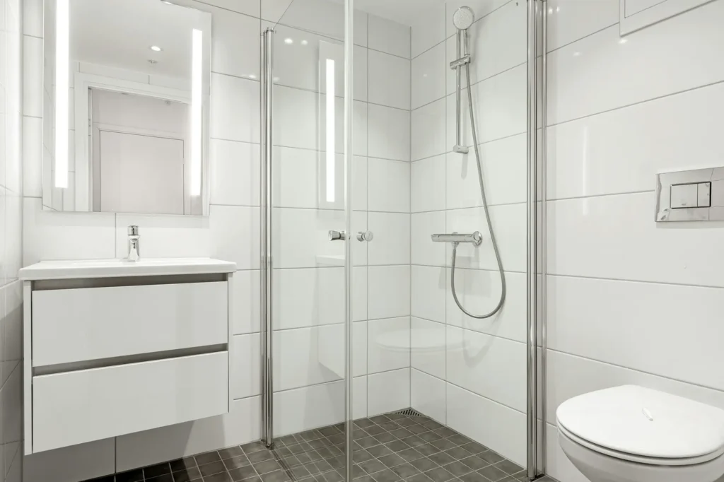 Bathroom in Burlington with glass shower enclosure, chrome handheld showerhead, floating vanity with mirror, and wall-mounted toilet