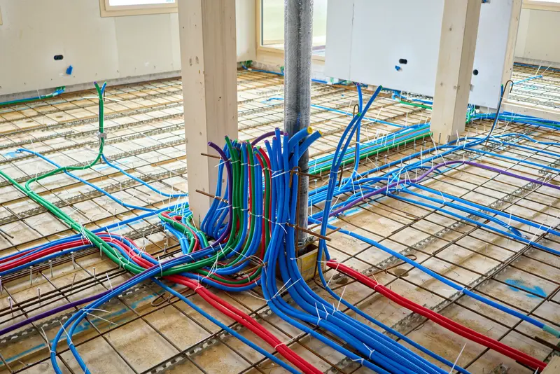 Radiant floor heating pipes installed over mesh grid before concrete pour, part of a heated bathroom floor installation in Burlington