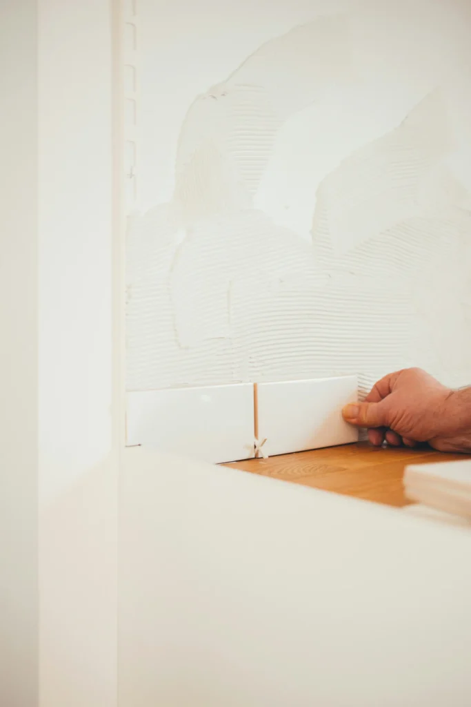 A Burlington tile installer setting a wall tile precisely, using spacers over troweled adhesive to keep the line level