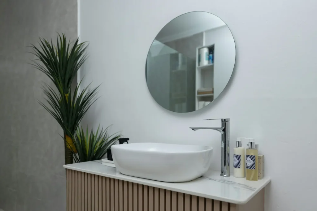 Sleek bathroom vanity with round mirror and wood cabinetry in Burlington