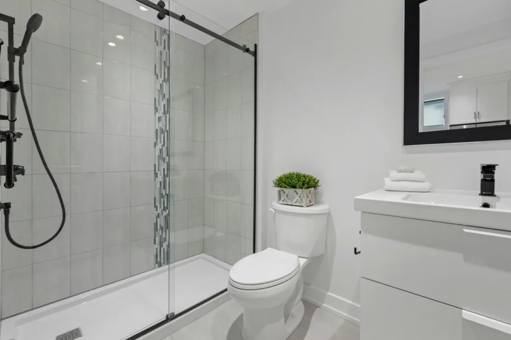 Sliding glass shower enclosure with tiled walls and mosaic accent strip in a Roseland, Burlington bathroom tub-to-shower conversion