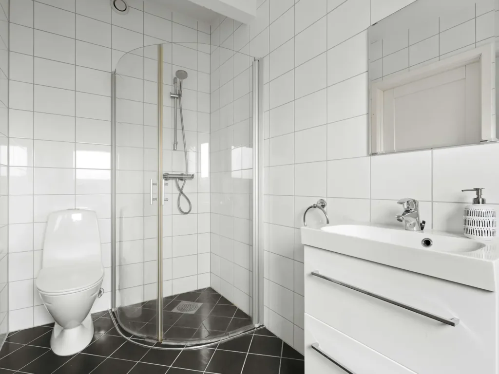 Compact curved glass shower enclosure with white tile after a tub-to-shower conversion, next to a modern vanity
