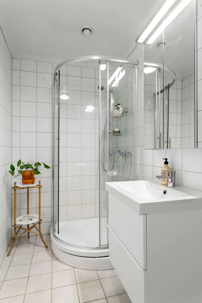 Compact curved glass shower stall with white tile walls after a tub-to-shower conversion in an Alton Village, Burlington bathroom