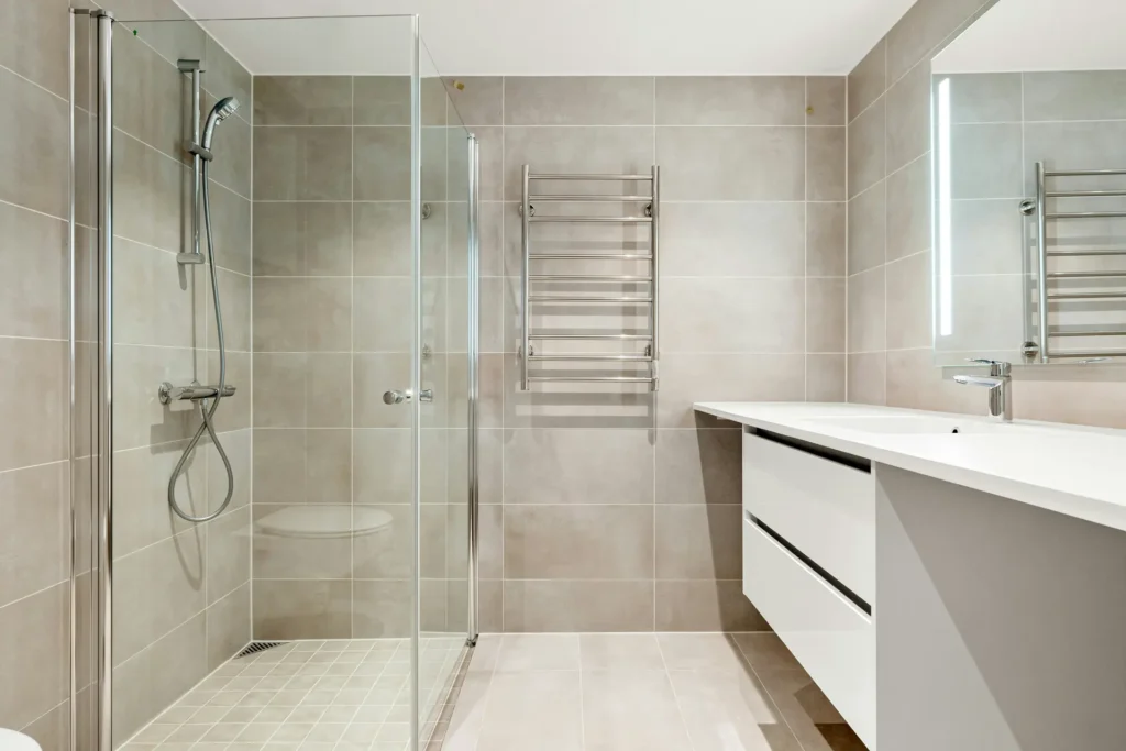 Compact glass shower enclosure with tile walls after a tub-to-shower conversion, next to a modern floating vanity