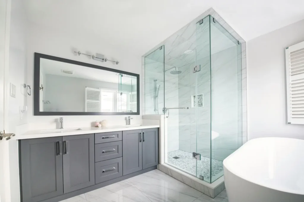 Walk-in custom shower in Headon Forest, Burlington with a frameless glass enclosure, marble tile walls, rain shower head, and a gray double vanity