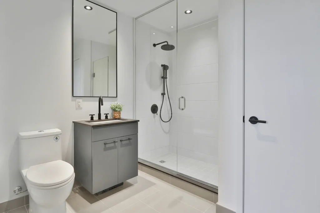 Modern walk-in glass shower with a matte-black grab bar and handheld showerhead in a Burlington bathroom